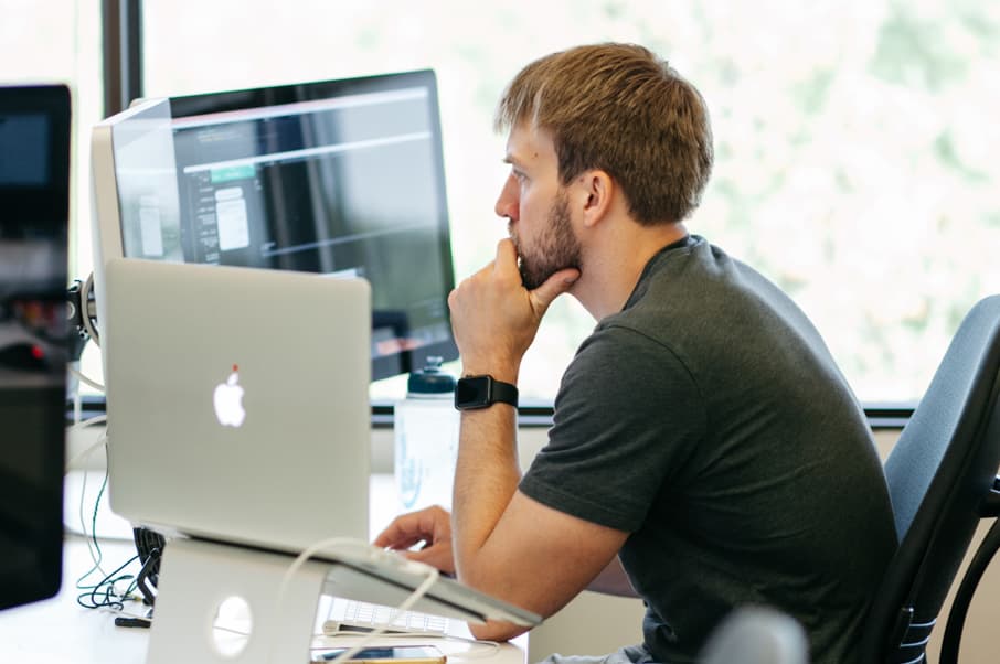 Engineer thinking intently in front of screen of code